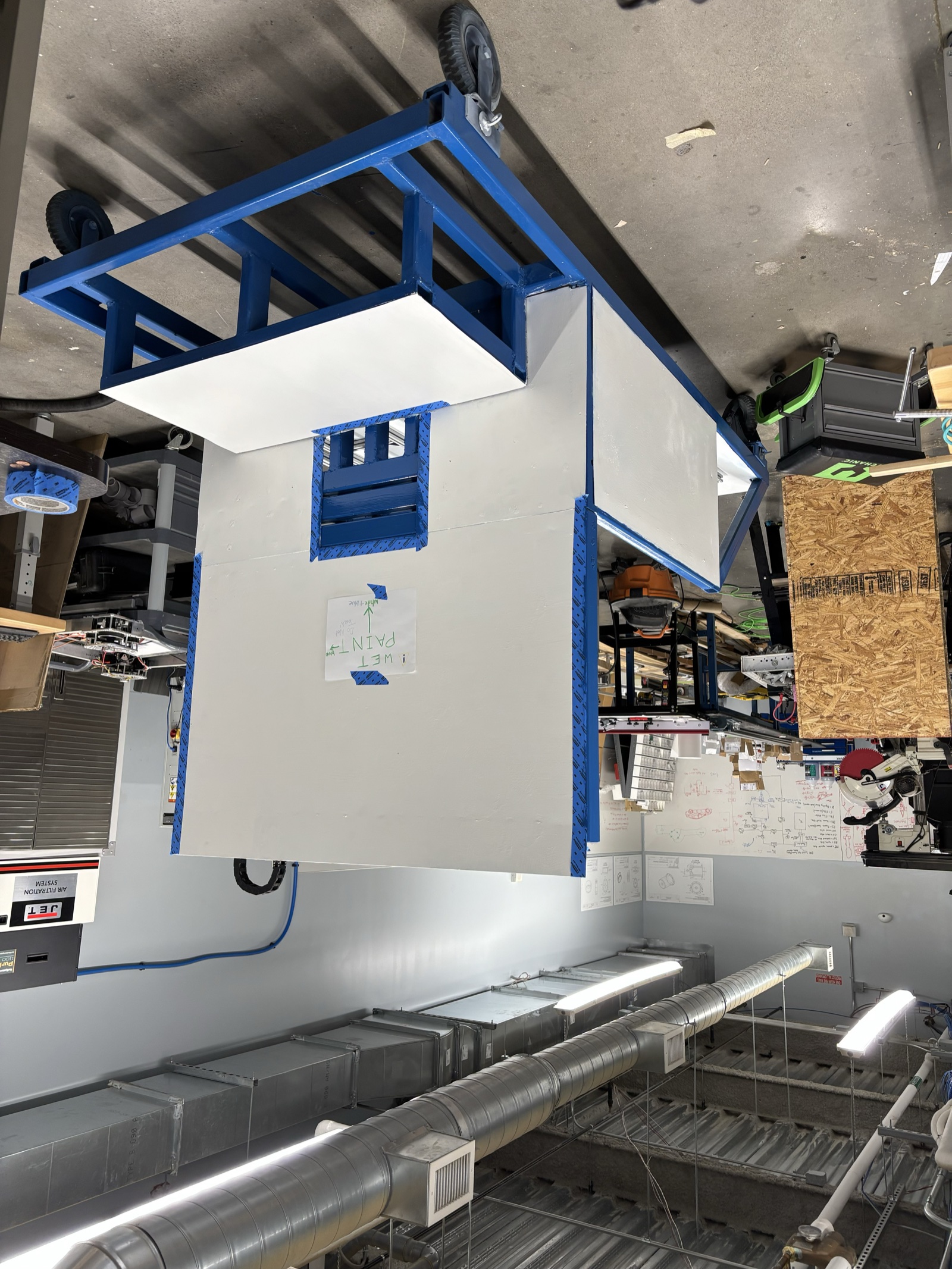 Freshly painted test stand drying with a wet paint sign